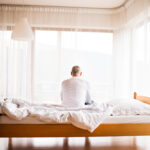 Senior man sitting on bed at home.