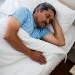 Senior man sleeping on bed in bedroom