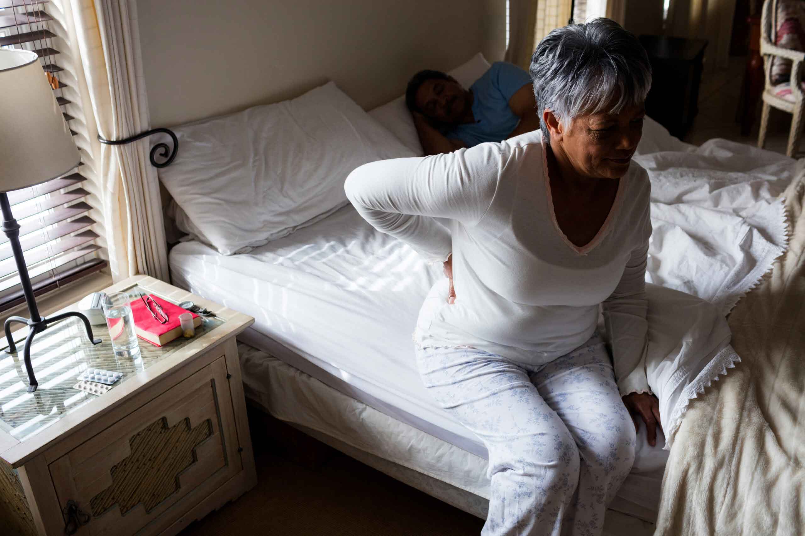 Senior woman suffering from back pain in bedroom
